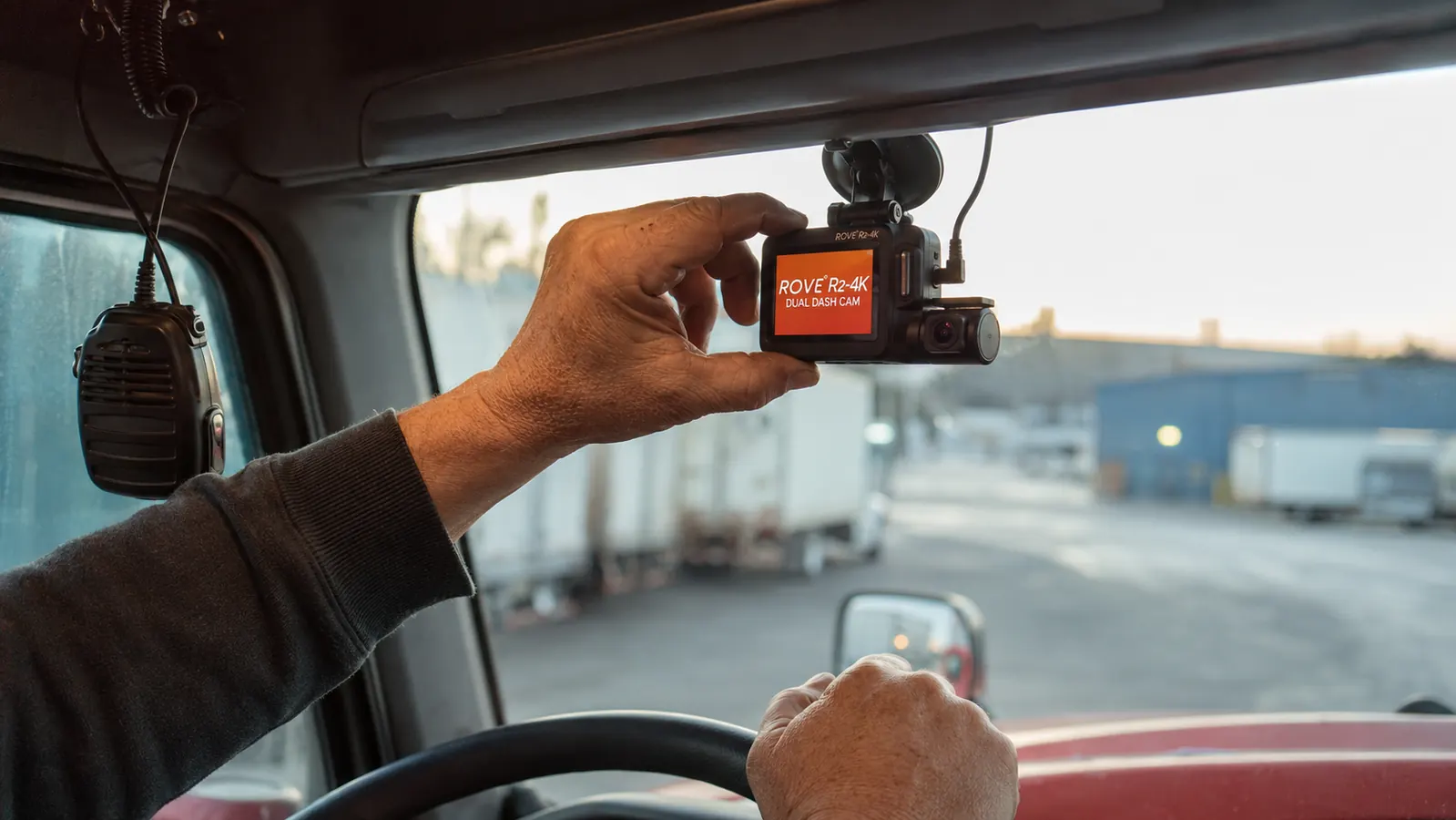 ROVE R2-4K dash cam mounted on truck windshield, driver's hand adjusting camera angle