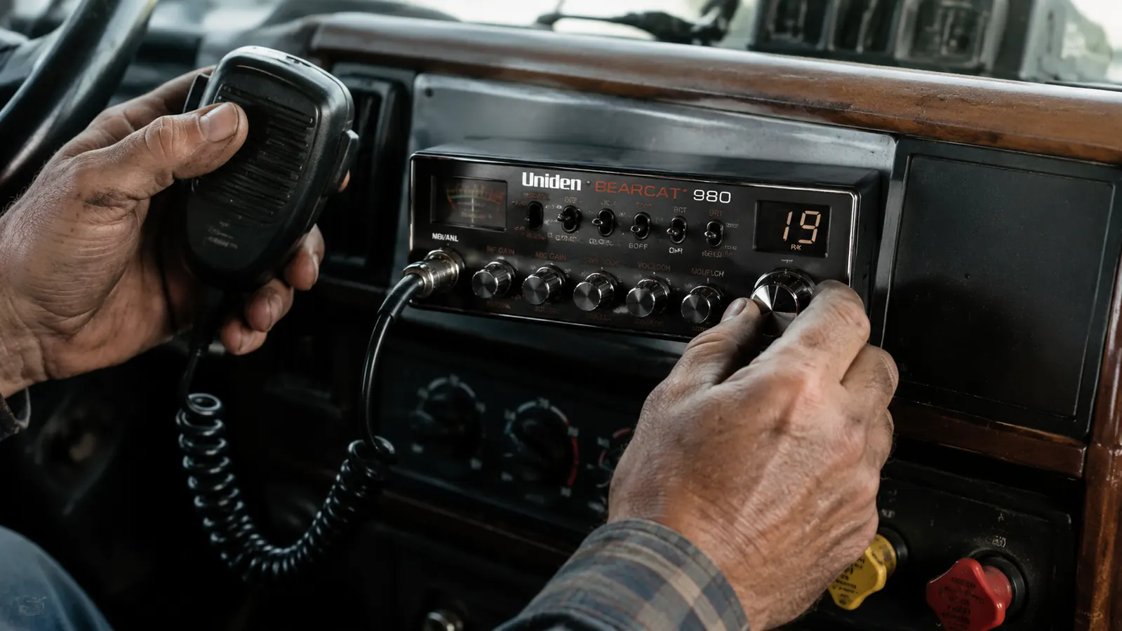 Hand reaching for the BEARCAT 980 volume and squelch knobs on a mounted dash bracket