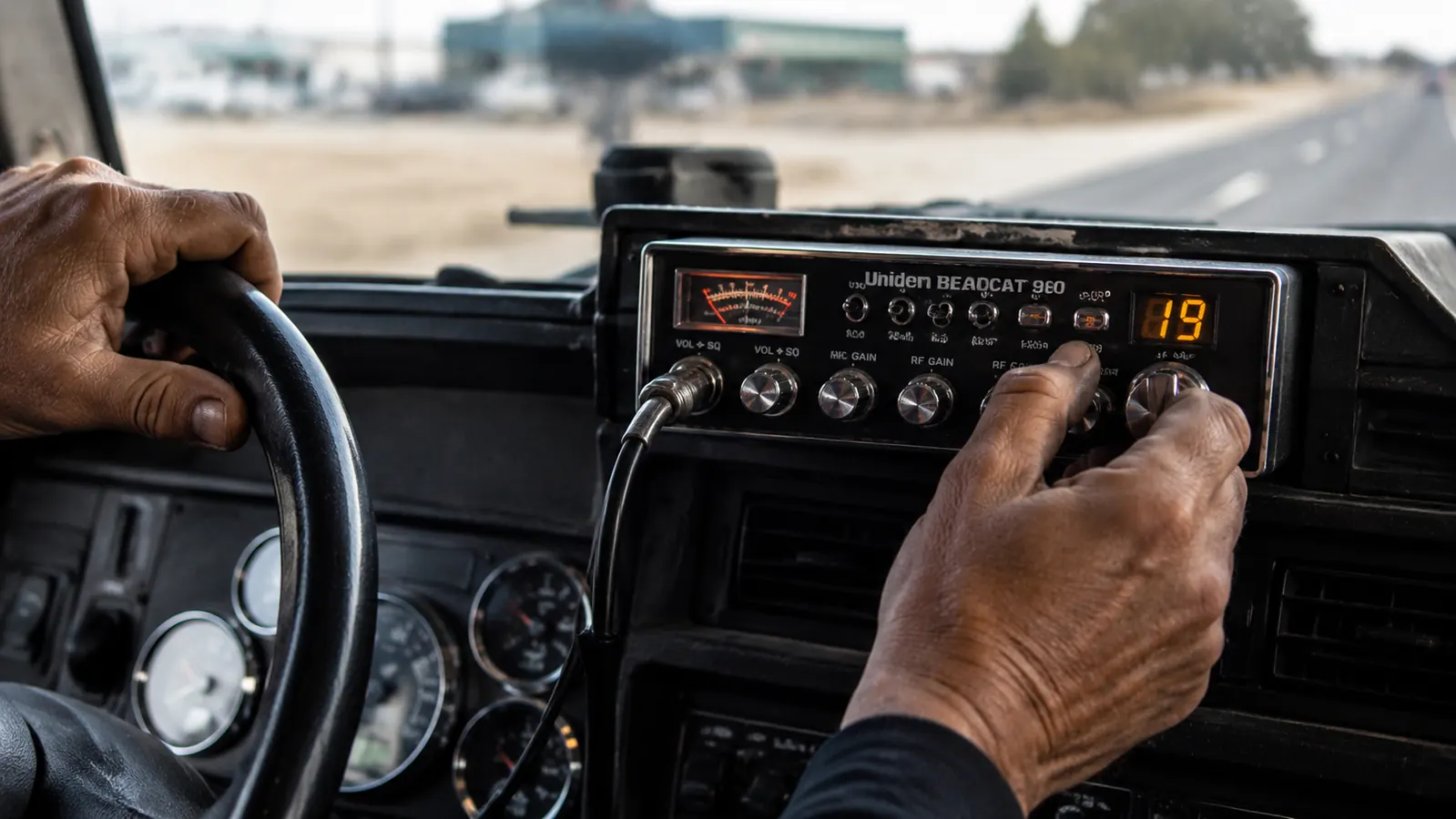Driver's hand adjusting the squelch knob on the Uniden BEARCAT 980 while rolling down the highway
